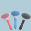 Three pet grooming brushes for dogs in pink, blue, and gray with ergonomic handles